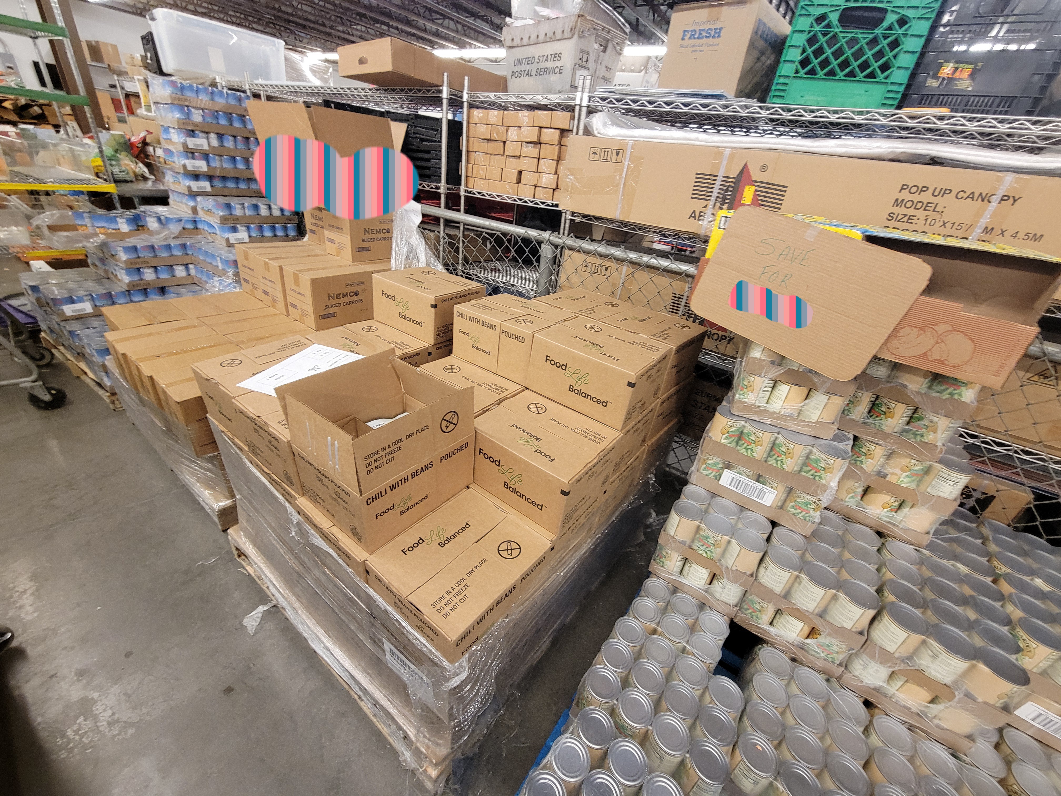 Pallets of food with a sign that says to save a product for someone on one, and cage plus shelf behind it.